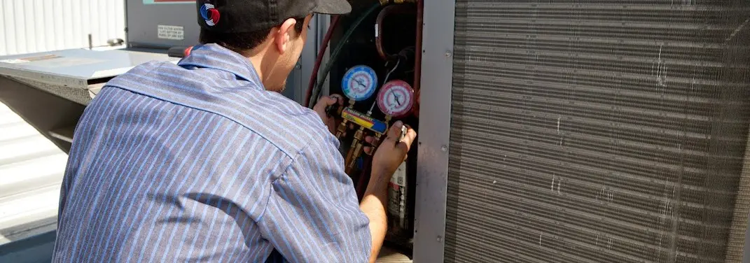 HVAC technician servicing a condenser unit in Arvin