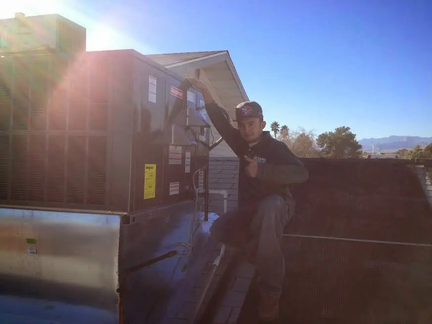 HVAC technician performing AC Tune-Up on a rooftop unit in Arvin